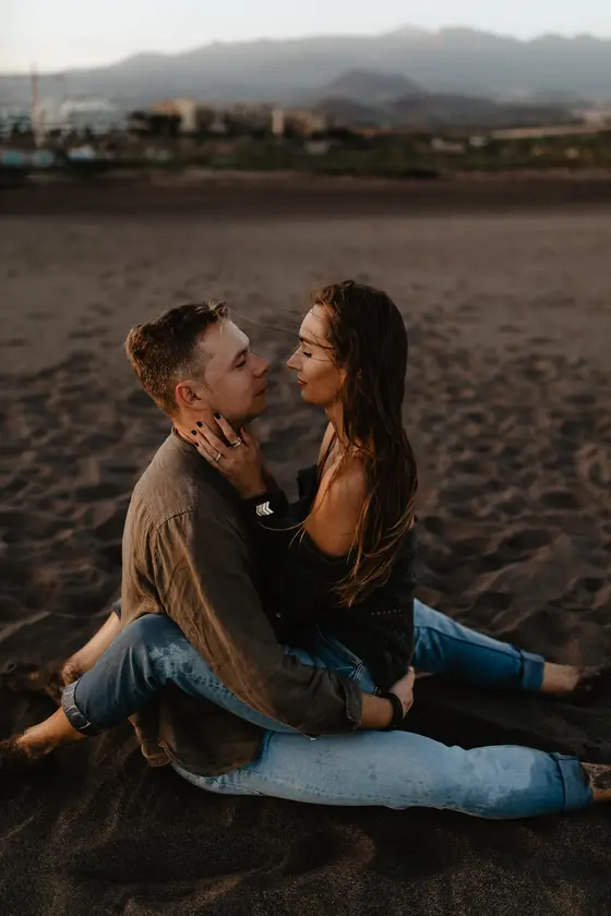 Romantyczny pocałunek pary na plaży La Tejita z górami w tle