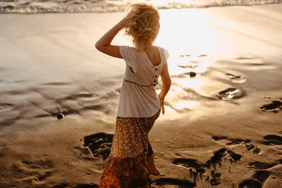 Young woman touching hair during contemplative moment in beach lifestyle photography session