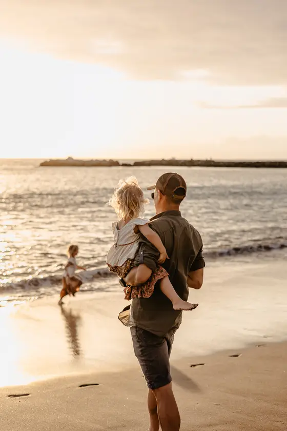 Father and daughter watching sunset over ocean in documentary lifestyle photography style